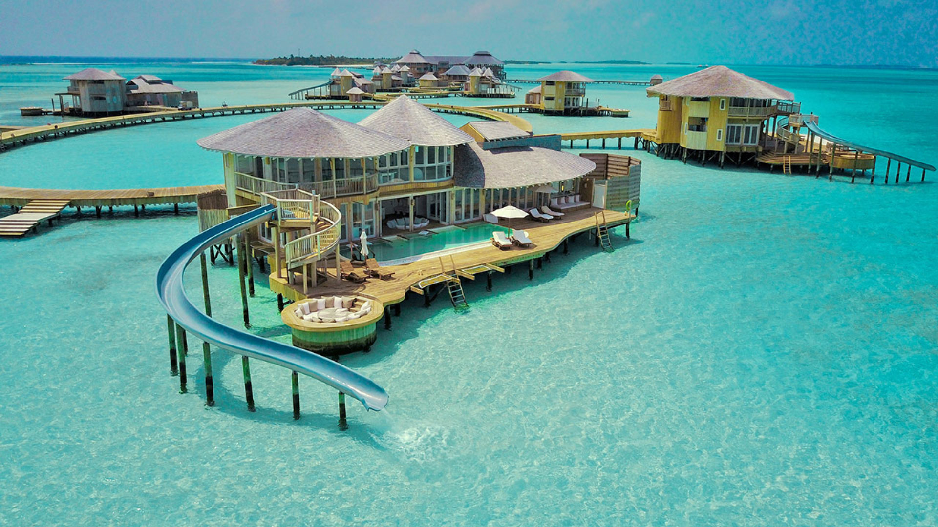 Overwater villa with a private water slide curving into a Maldives lagoon