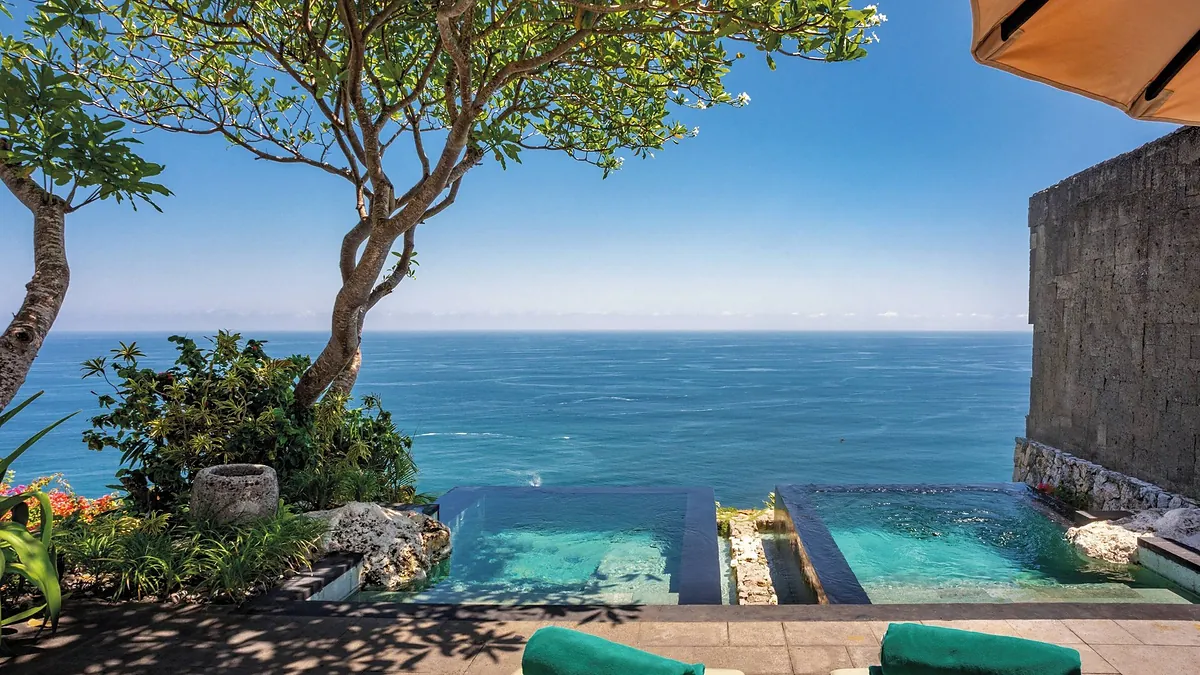 Infinity pool at Bvlgari Resort Bali with a plumeria tree and an unobstructed view of the Indian Ocean