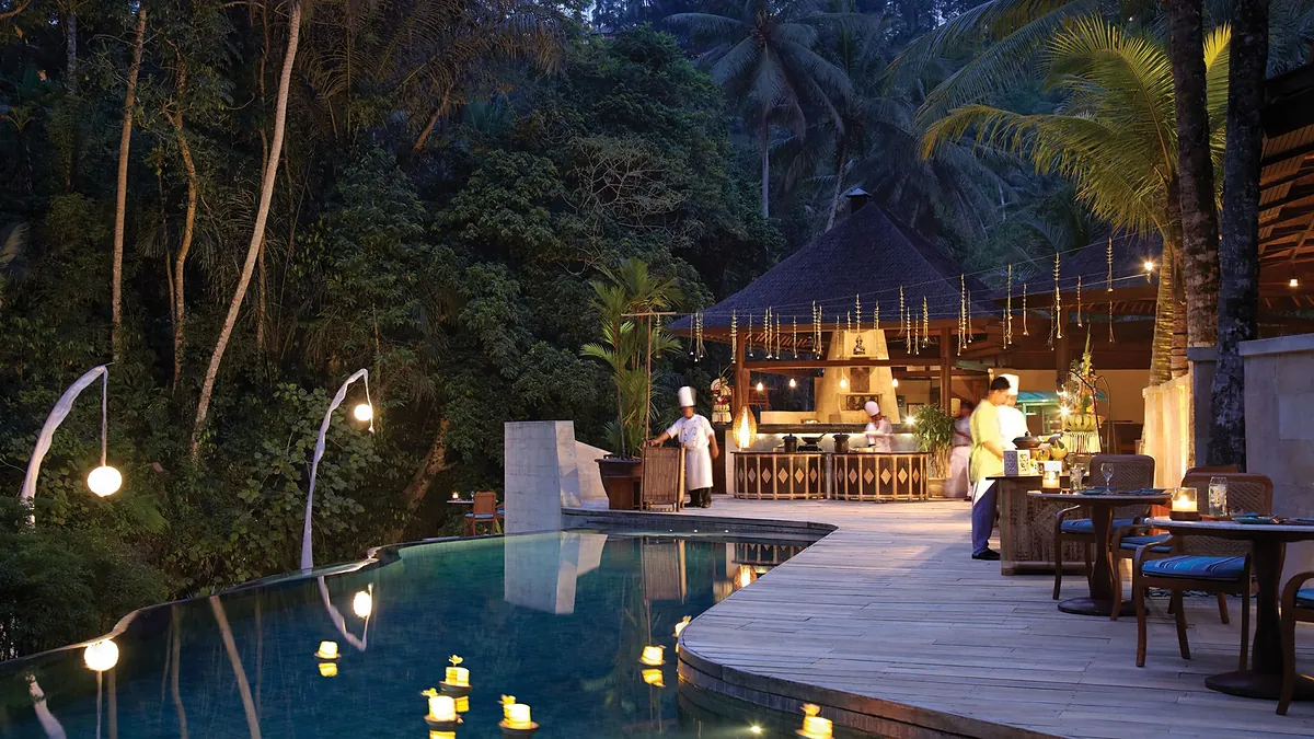 Dusk poolside dining with candles and chef stations in the jungle at Four Seasons Sayan