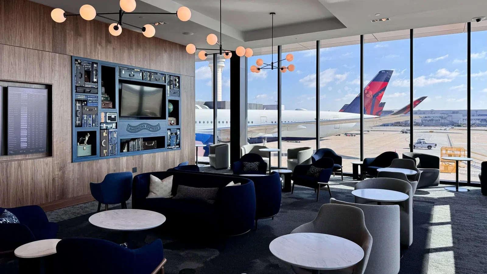 An airport lounge in the morning peak with travellers seated near wide windows