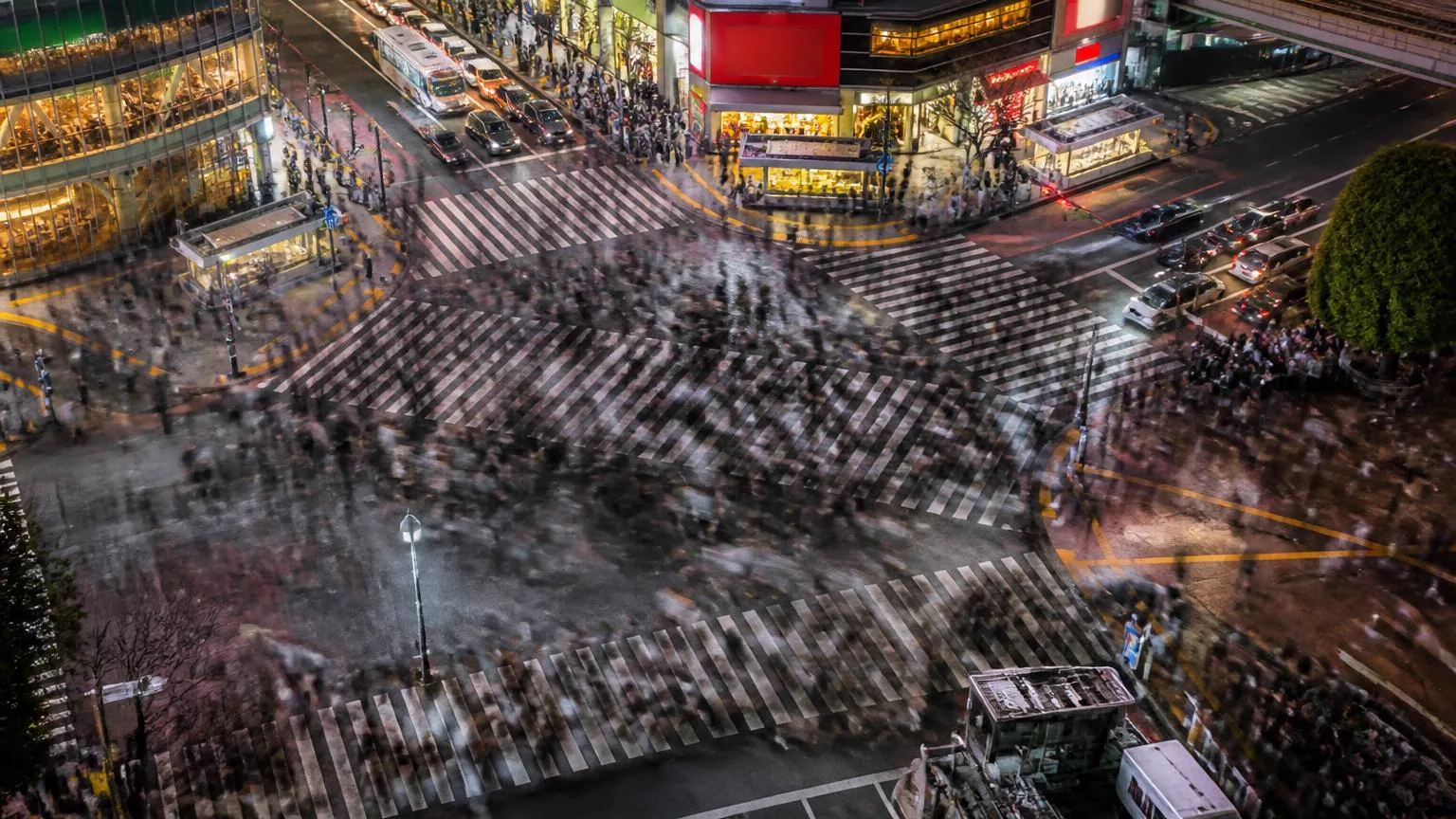 Dense crowd crossing Shibuya scramble crossing in Tokyo at dusk, long exposure