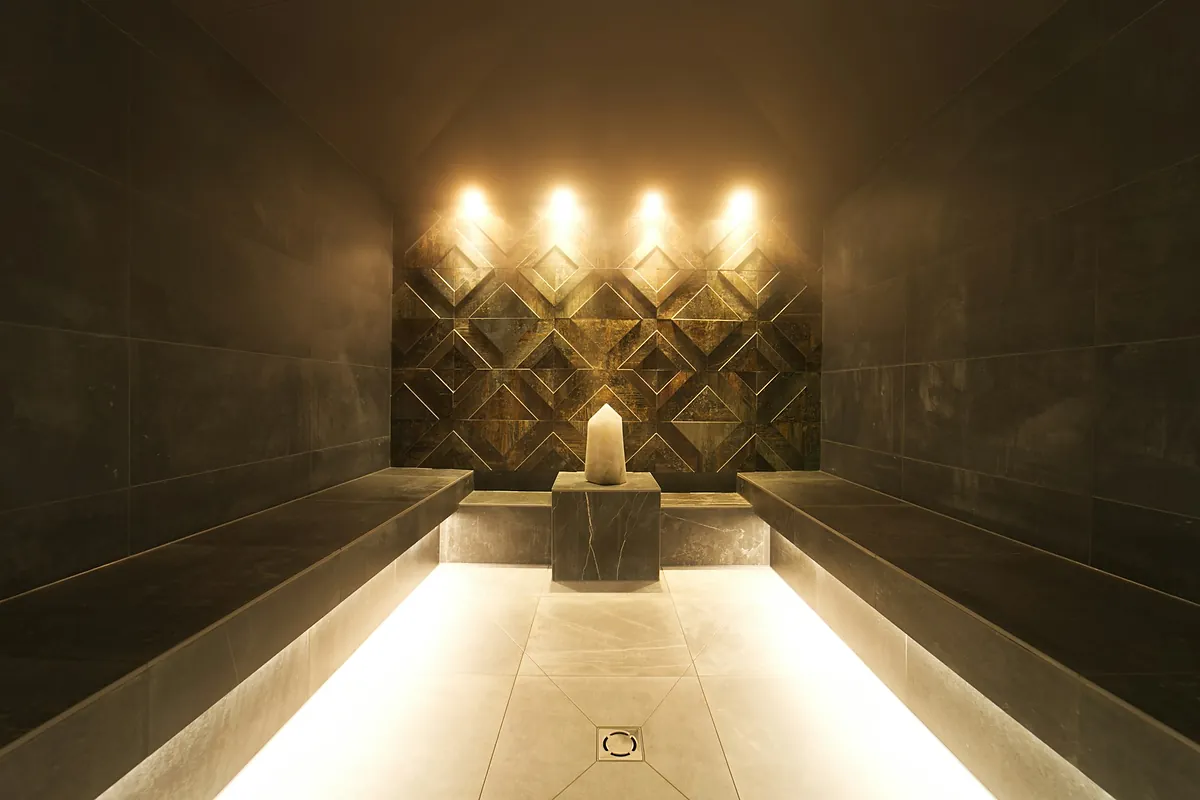A modern steam room in low light, stone lined with a lit niche at the far end