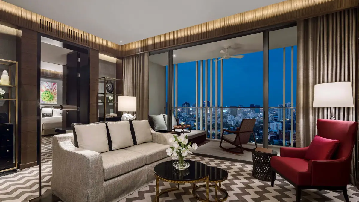 A suite living room with a pale sofa, a rocking chair and a red armchair by the window