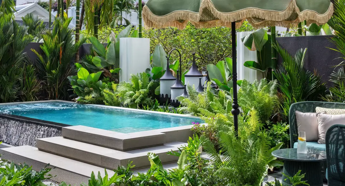 A small rectangular plunge pool surrounded by dense tropical planting and lanterns