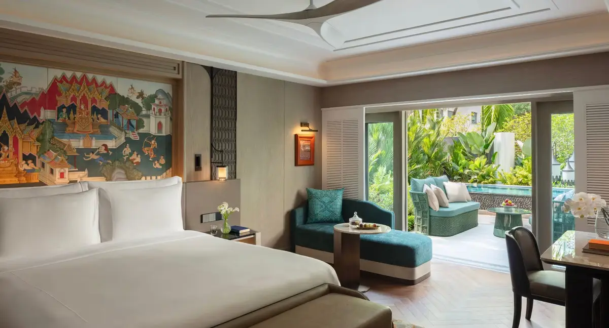 A bedroom with a Thai mural and sliding doors opening onto a terrace and a pool