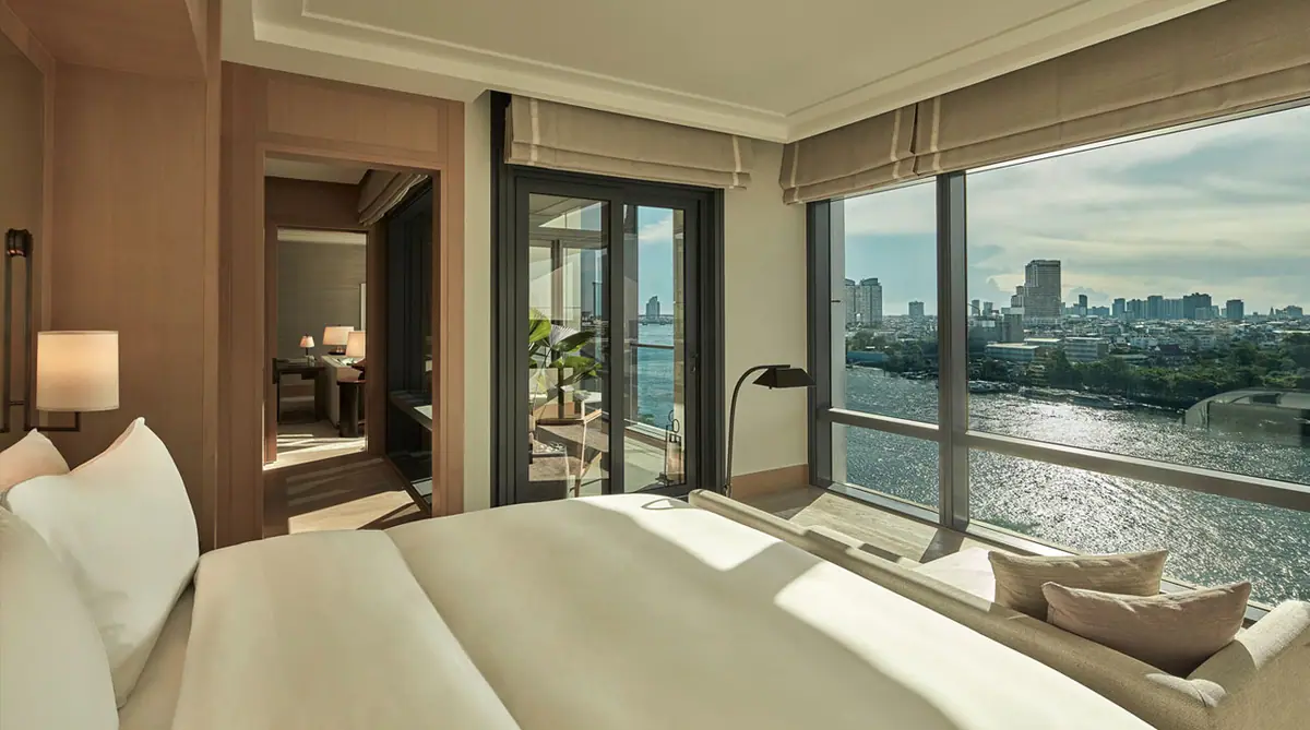 A suite bedroom with a daybed by the window and the river visible through full height glass
