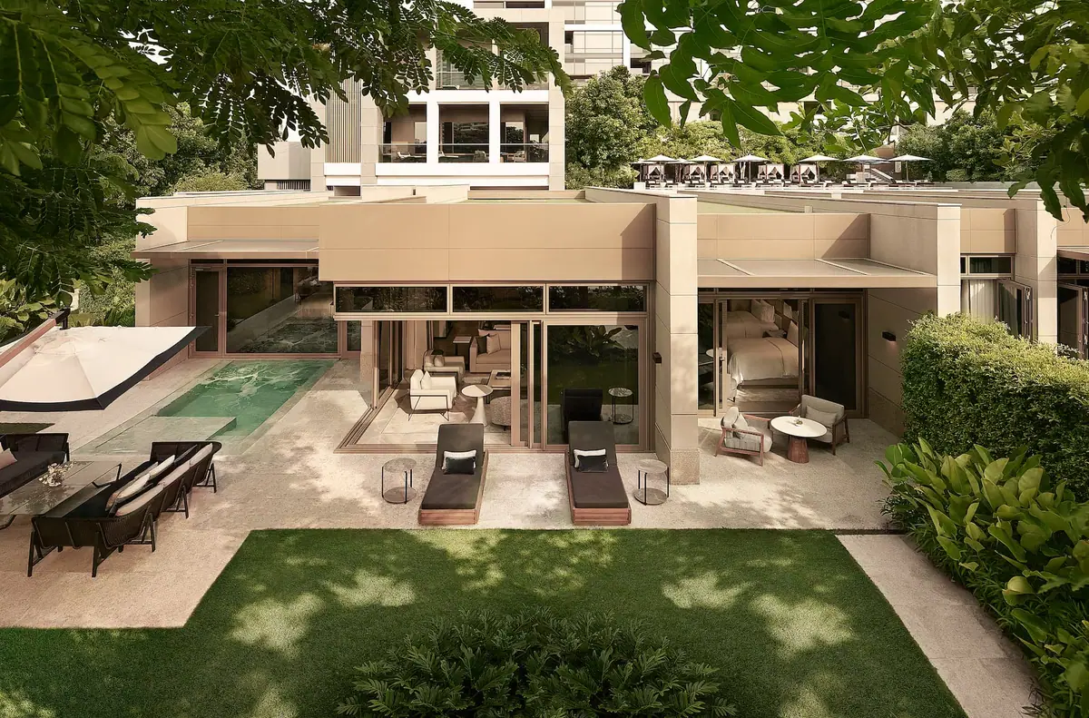 A single storey villa opening onto a private pool and a lawn under mature trees