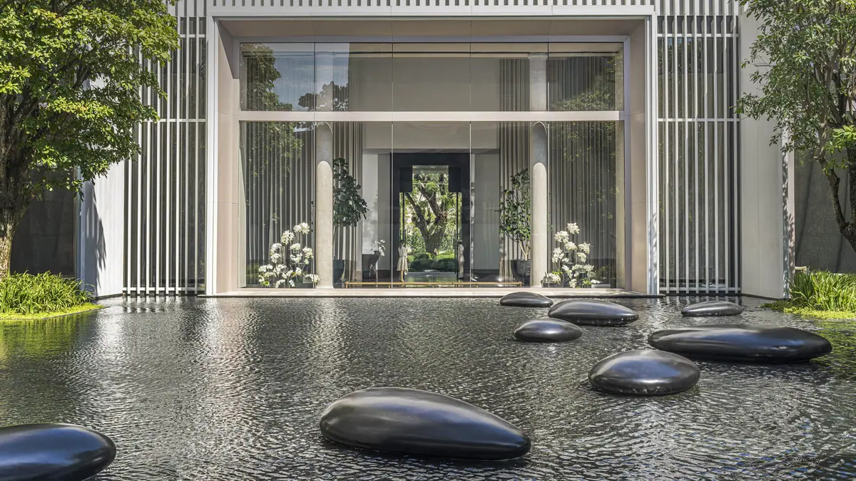 A still black reflecting pool with sculpted stones set in front of a tall colonnaded entrance