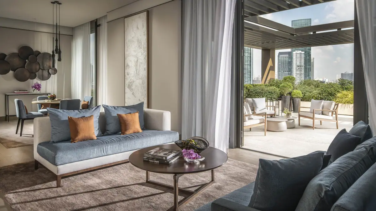 A suite living room in blue and cream opening onto a covered terrace above the river