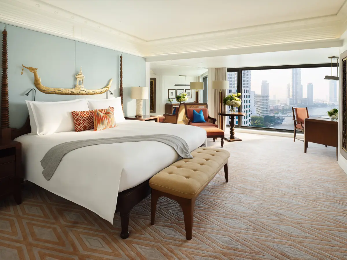 A river facing bedroom with a gilded boat headboard and a blue lotus rug