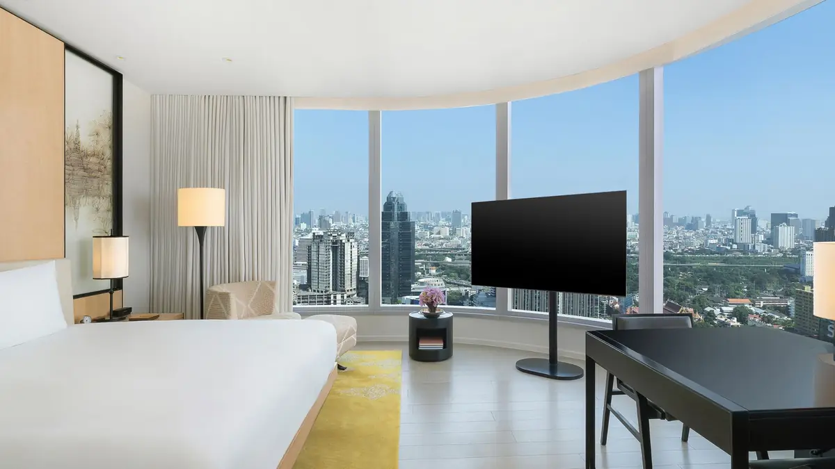 A king room at Park Hyatt Bangkok with a curved glass wall and a view over the city