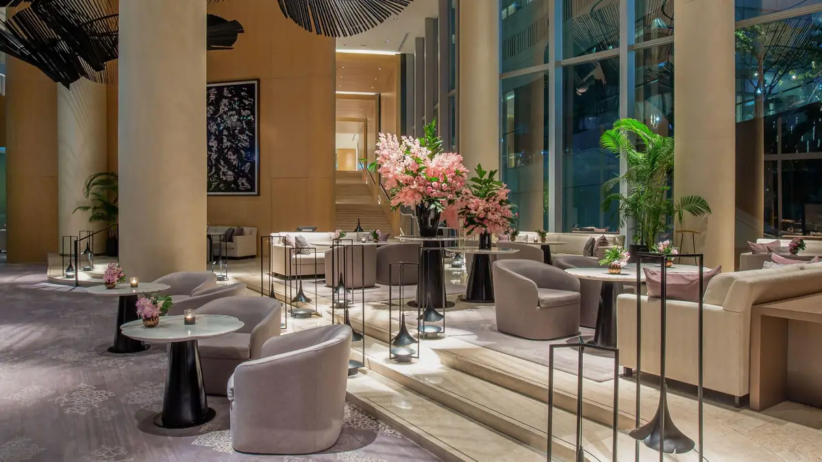The Living Room lounge at night, with tall windows, stone columns and blossom arrangements