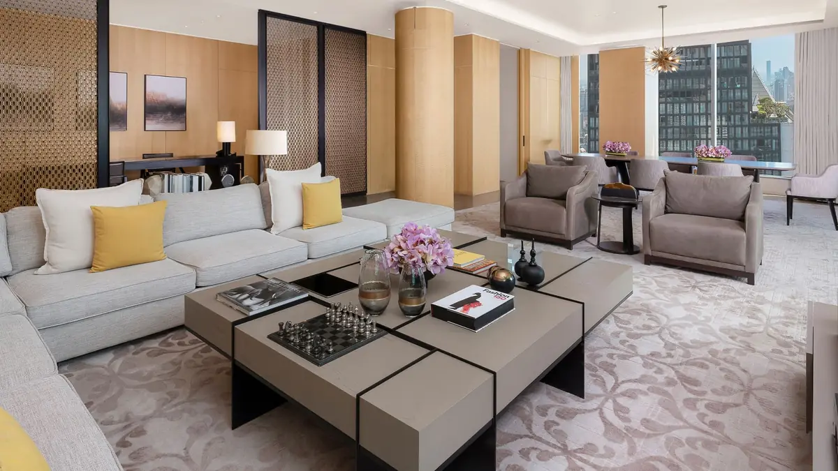 The living area of the Presidential Suite with pale sofas, a low table and windows onto the skyline
