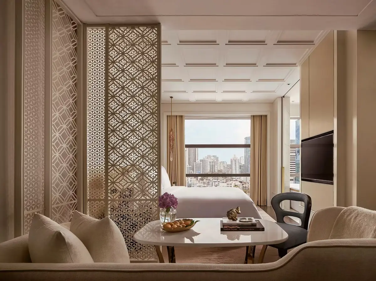 A bedroom behind a carved lattice screen with a round table and a window onto the city