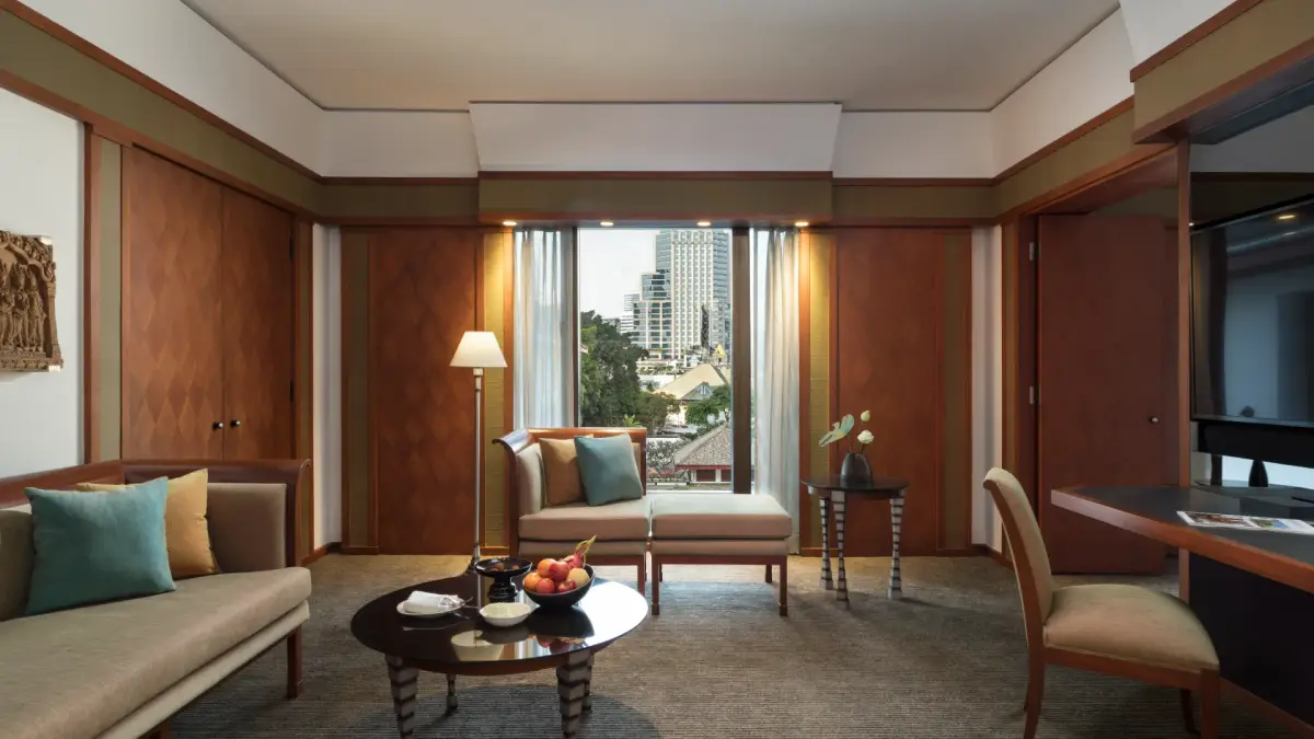 A suite sitting room with teak panelling, a grey sofa and windows onto the city