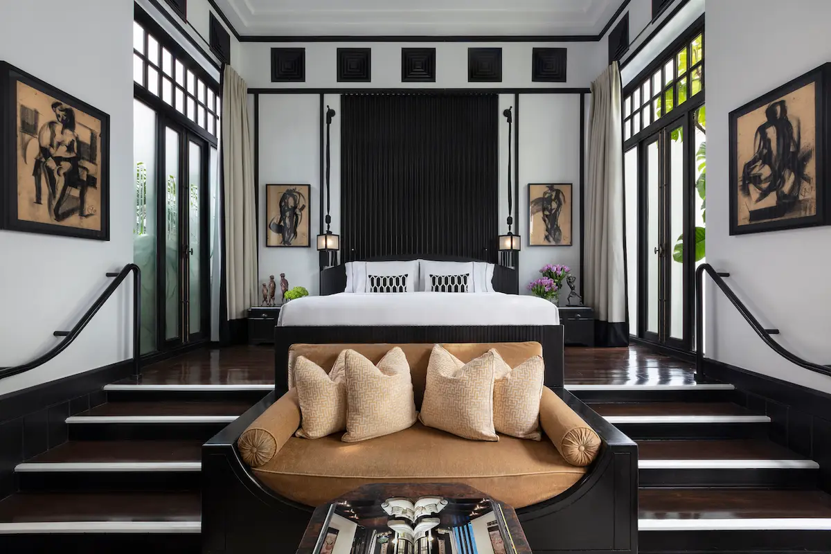 A dark panelled bedroom with a vintage bicycle against the wall and an armchair by the bed