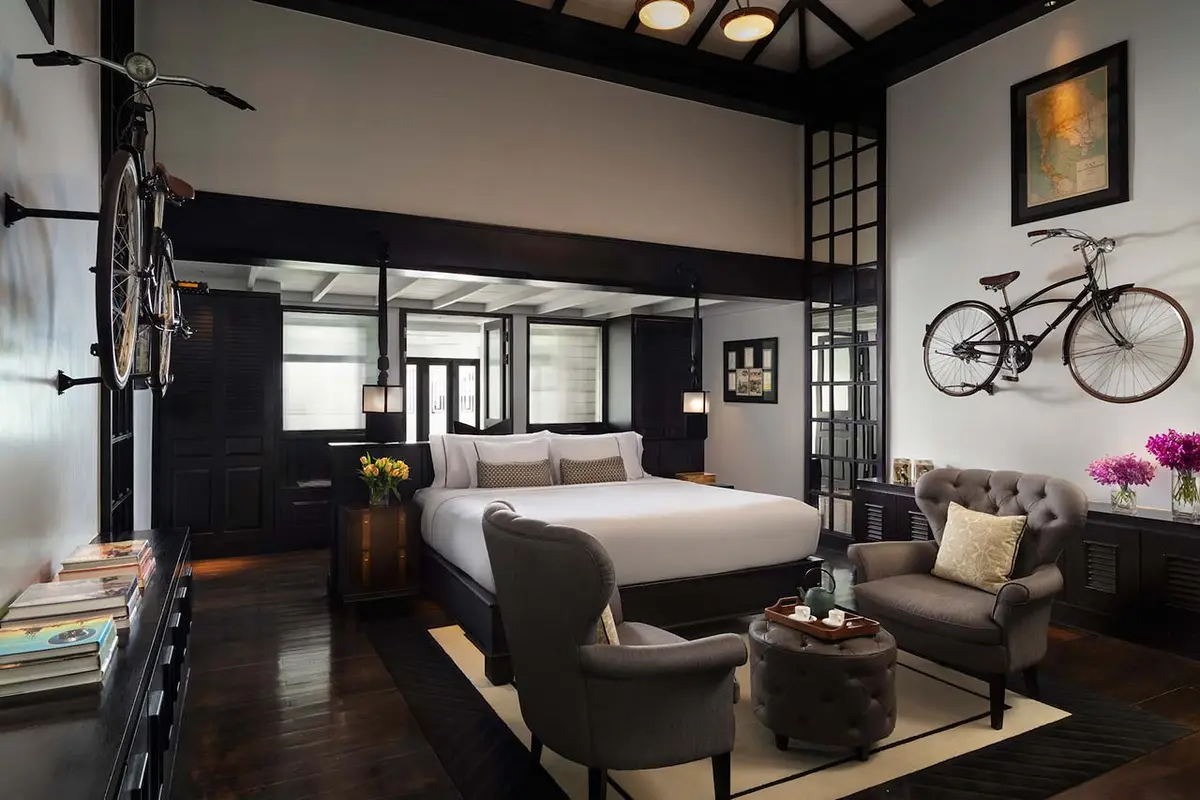 A high ceilinged black and white bedroom with a raised platform bed and framed prints