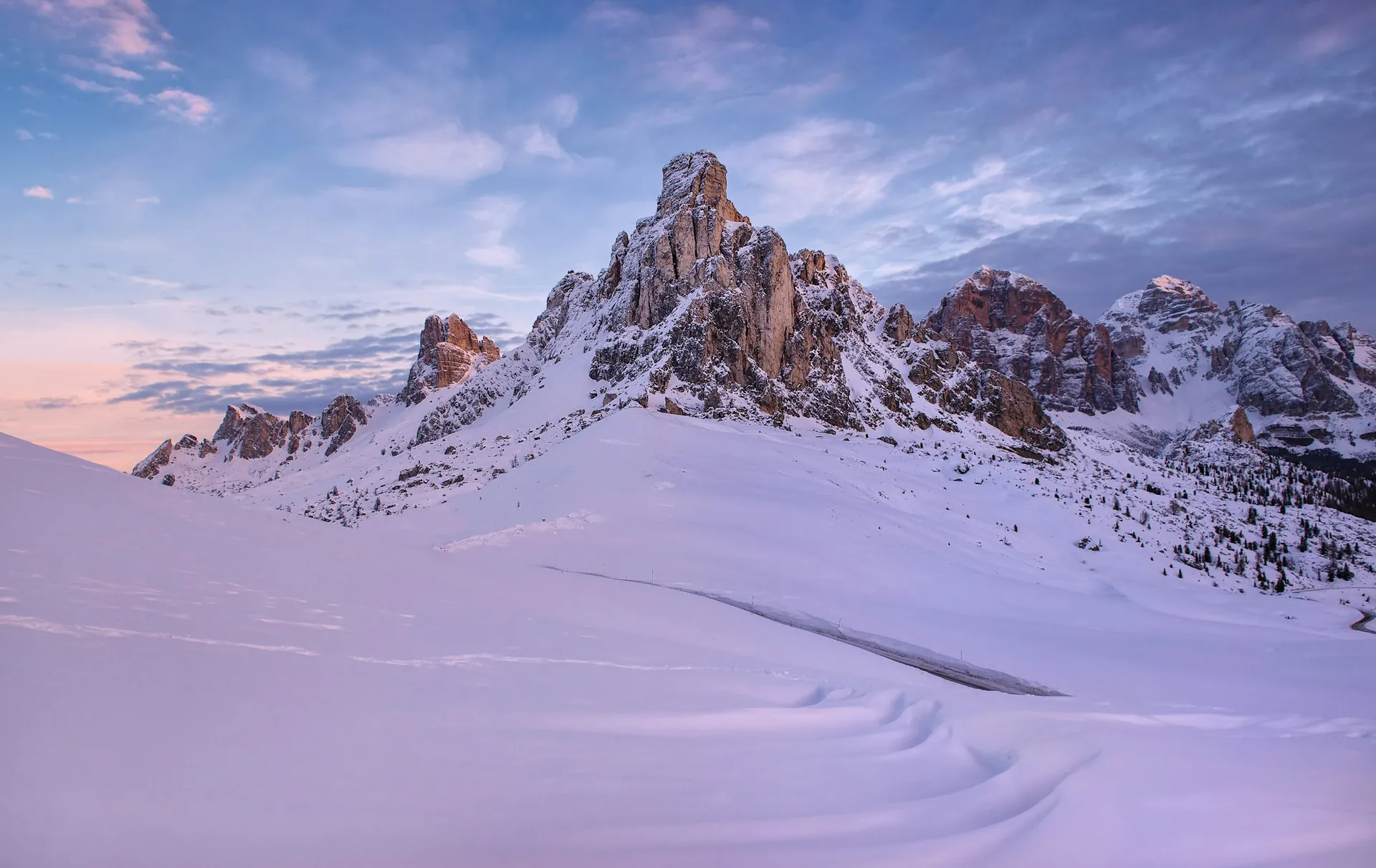 An untracked snowfield running up to bare rock walls at dusk