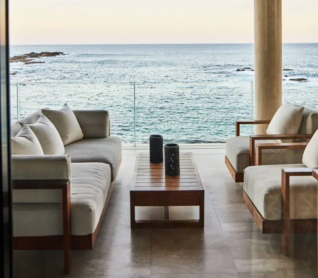 A living room with deep grey sofas opening directly onto rocks and open sea