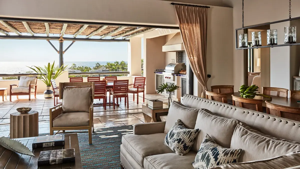 A living room with deep sofas and lanterns opening onto a covered terrace and the sea