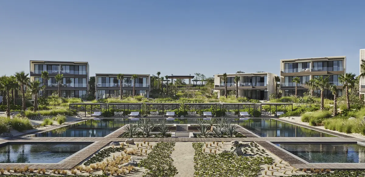 A formal water garden of shallow pools and planted beds between two low buildings