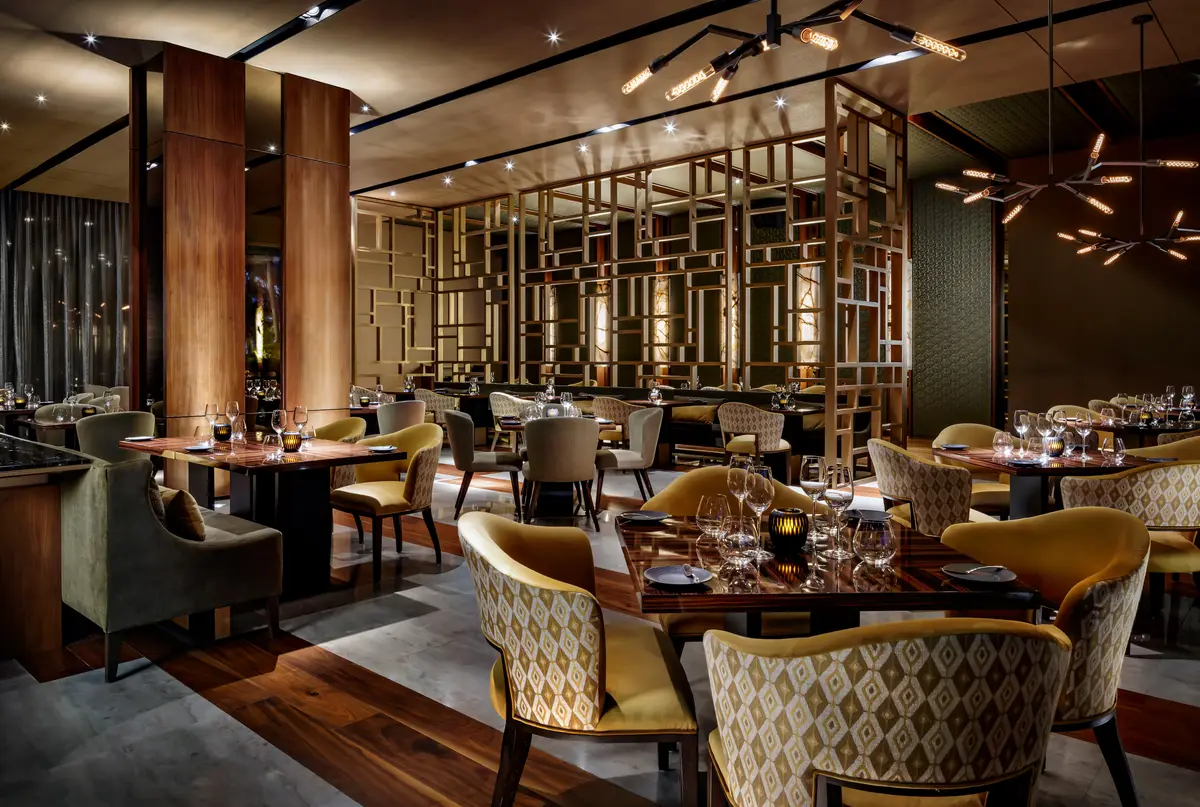 A dark panelled dining room with upholstered chairs and a screen of vertical timbers