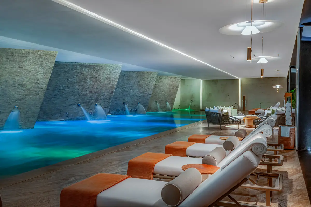 An indoor hydrotherapy pool with water jets falling from a stone wall