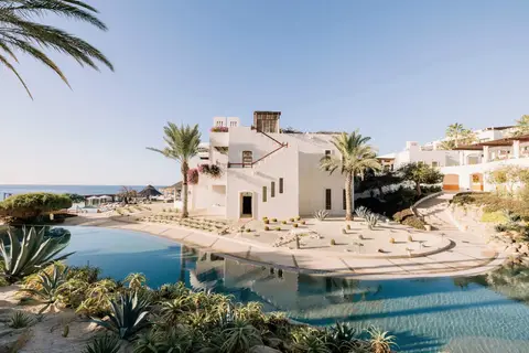 White domed buildings and a curving pool above a beach in early morning light