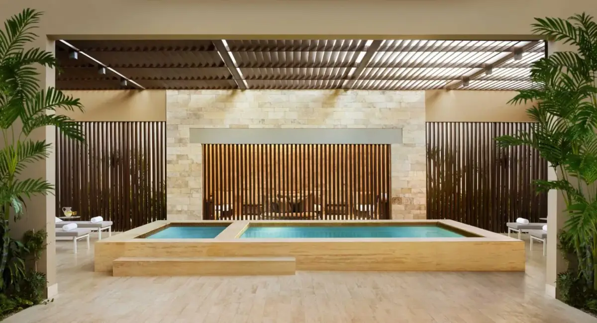 A stone lined indoor pool flanked by timber screens and loungers