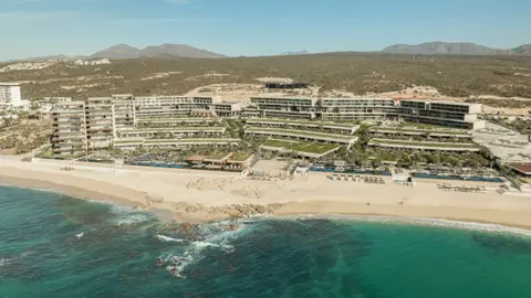 A long terraced resort stepping down a slope to a pale beach and turquoise water