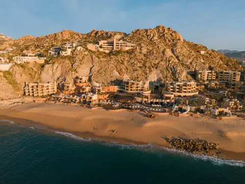 The resort built into a rocky headland above a long Pacific beach, seen from the air