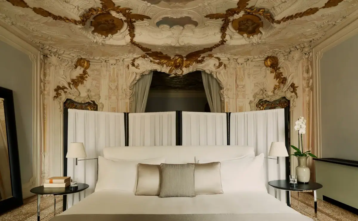 A bed beneath a painted and gilded eighteenth century ceiling