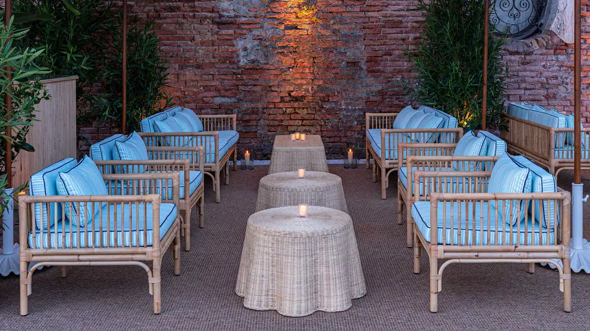 A courtyard with blue upholstered benches against an old brick wall
