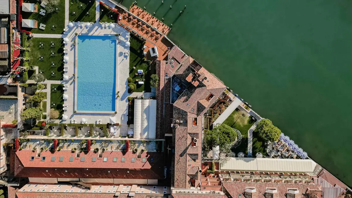An aerial view of a large pool and formal gardens on an island beside a lagoon