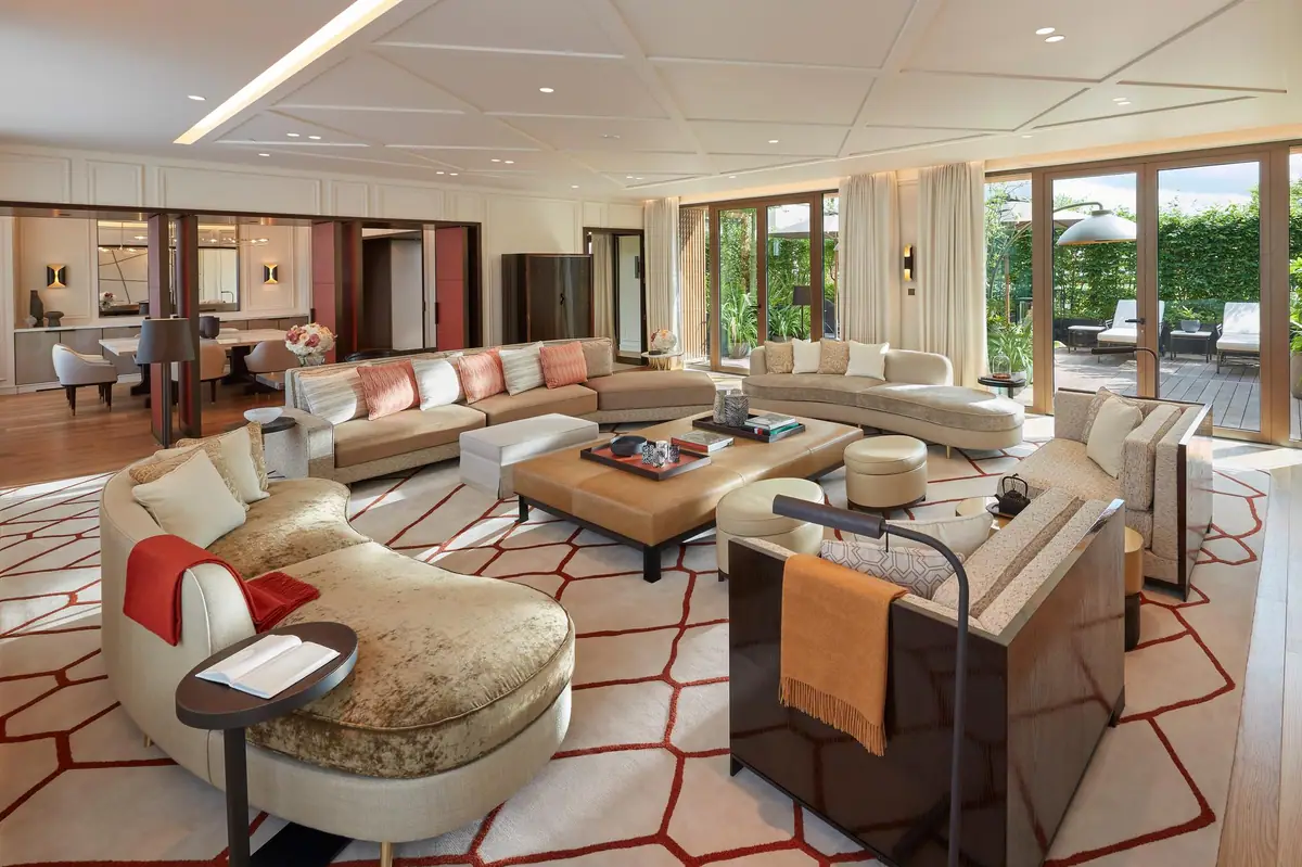 A large sitting room with cream sofas and a patterned rug under a low ceiling