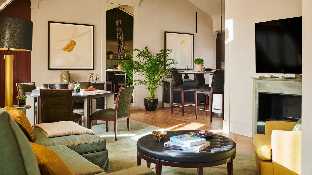 A sitting room with a fireplace, a dark dining table and a pale sofa
