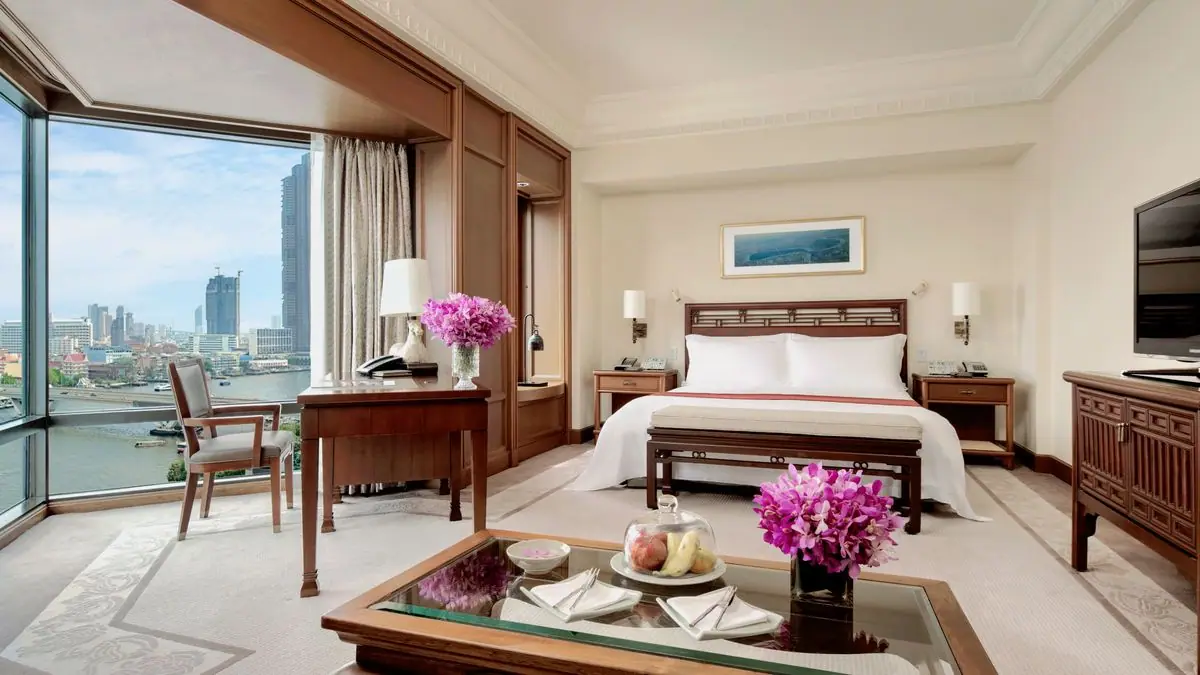 A bedroom with pale walls and a window onto a wide river