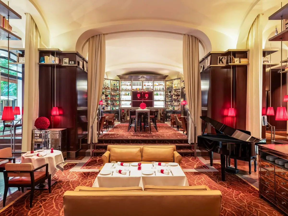 A room with arched glass doors, red shaded lamps and a grand piano