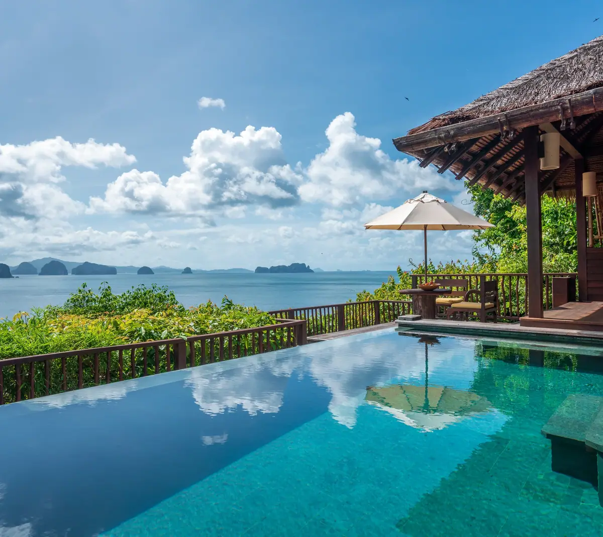 An infinity pool and a thatched pavilion looking out to limestone islands
