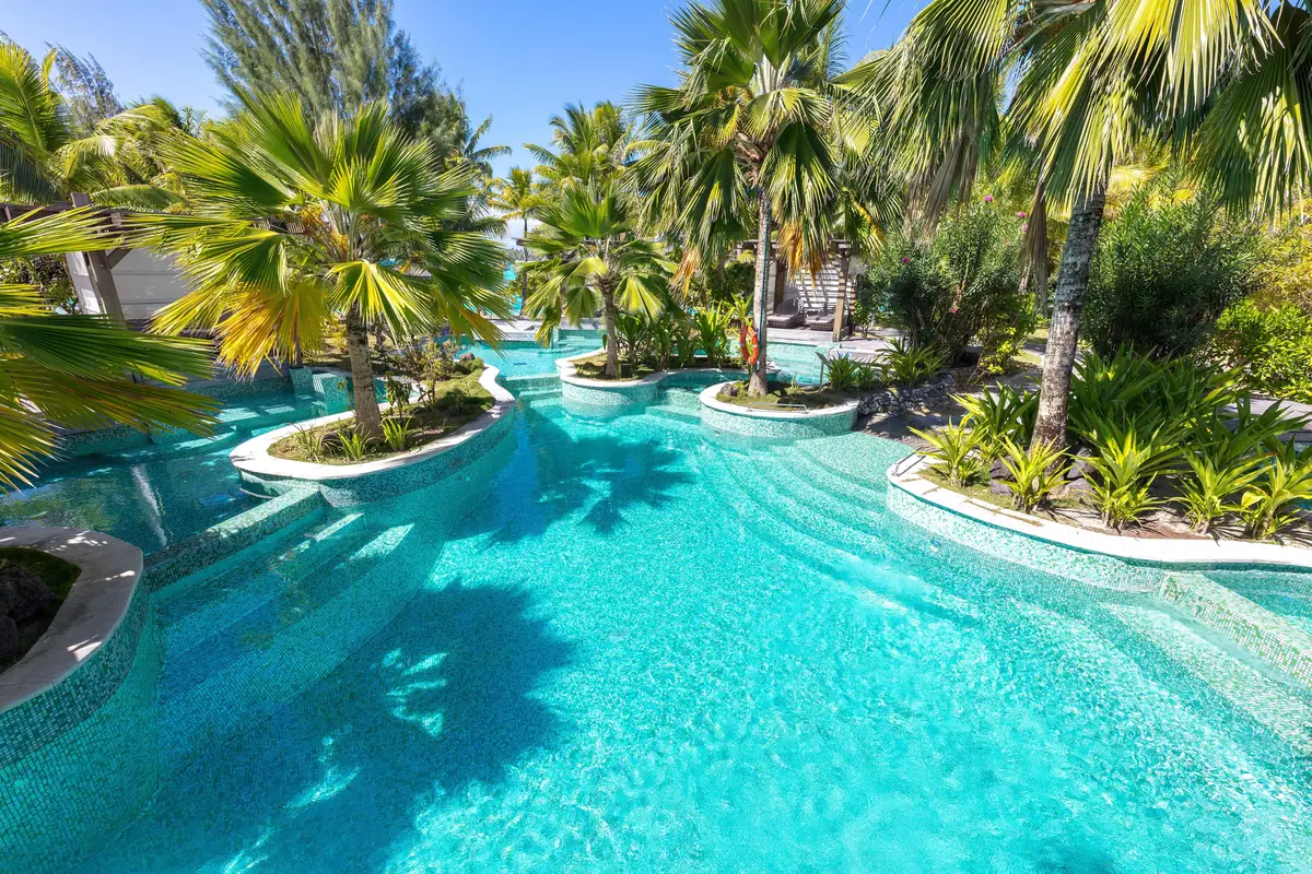 A large lagoon pool edged with palms and white sand