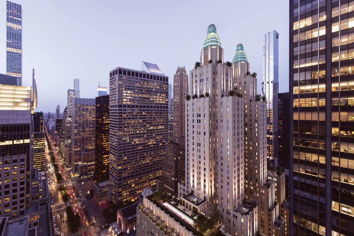 The limestone and brick towers of a tall 1931 hotel rising above a street at dusk