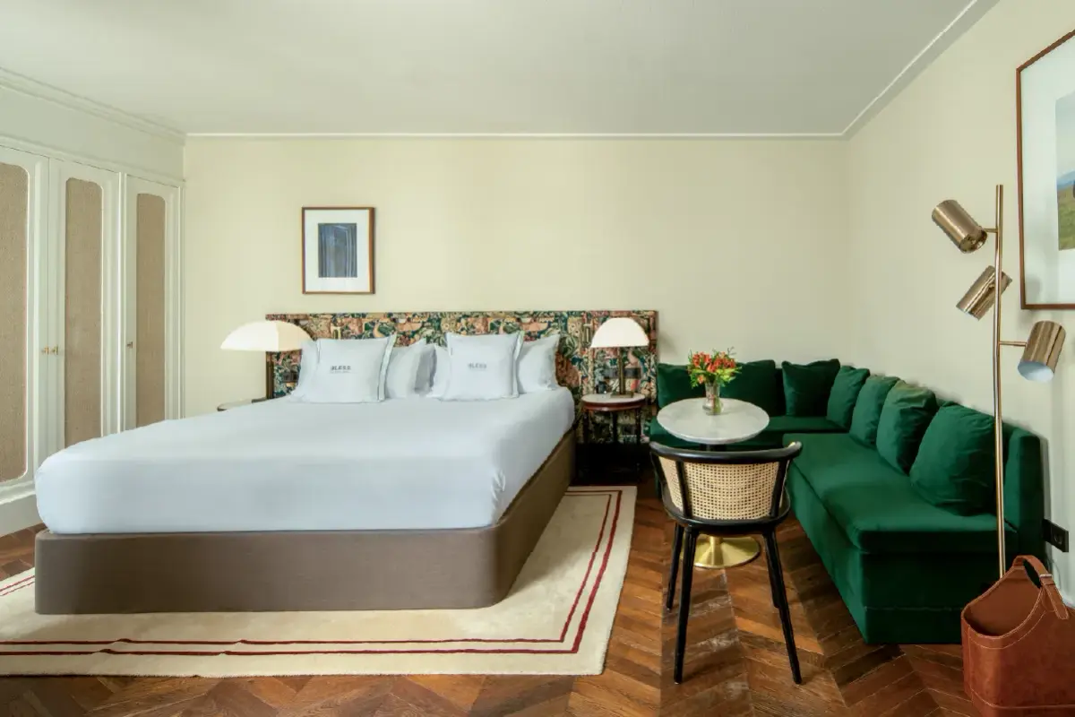 A guest room at Bless Hotel Madrid with a green velvet banquette beside the bed