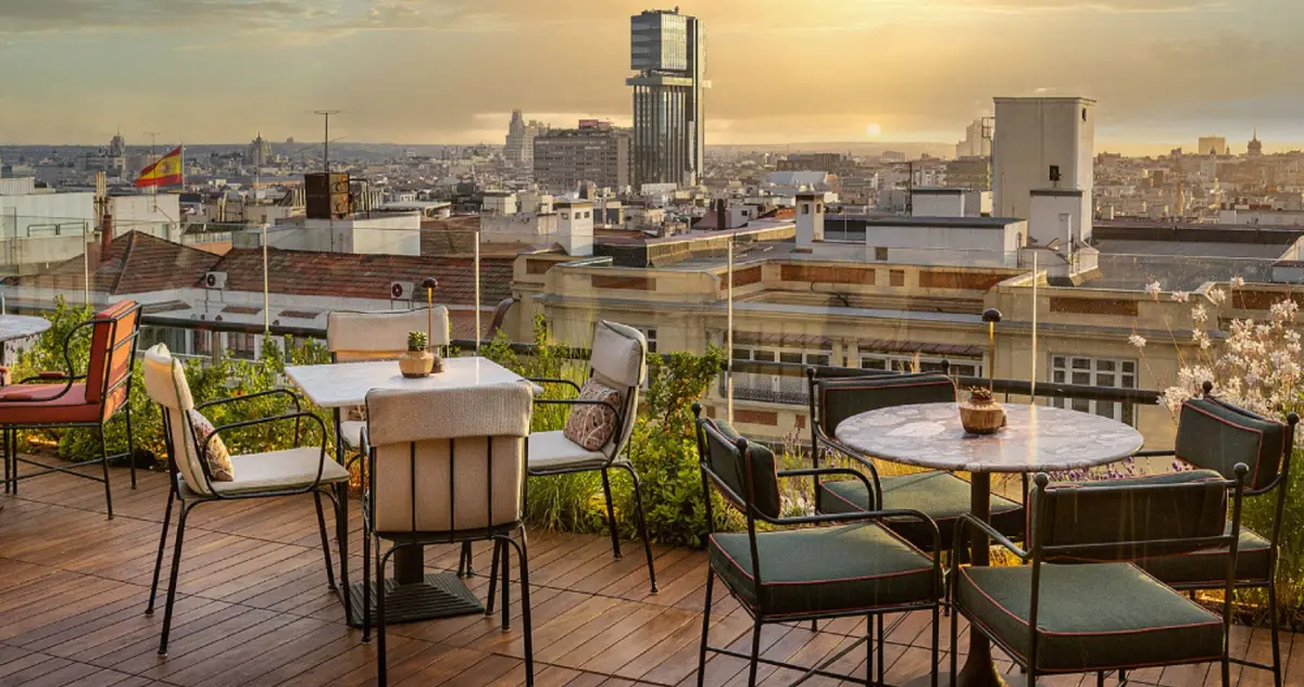 The rooftop terrace at Bless Hotel Madrid at sunset with tables and the Madrid skyline behind