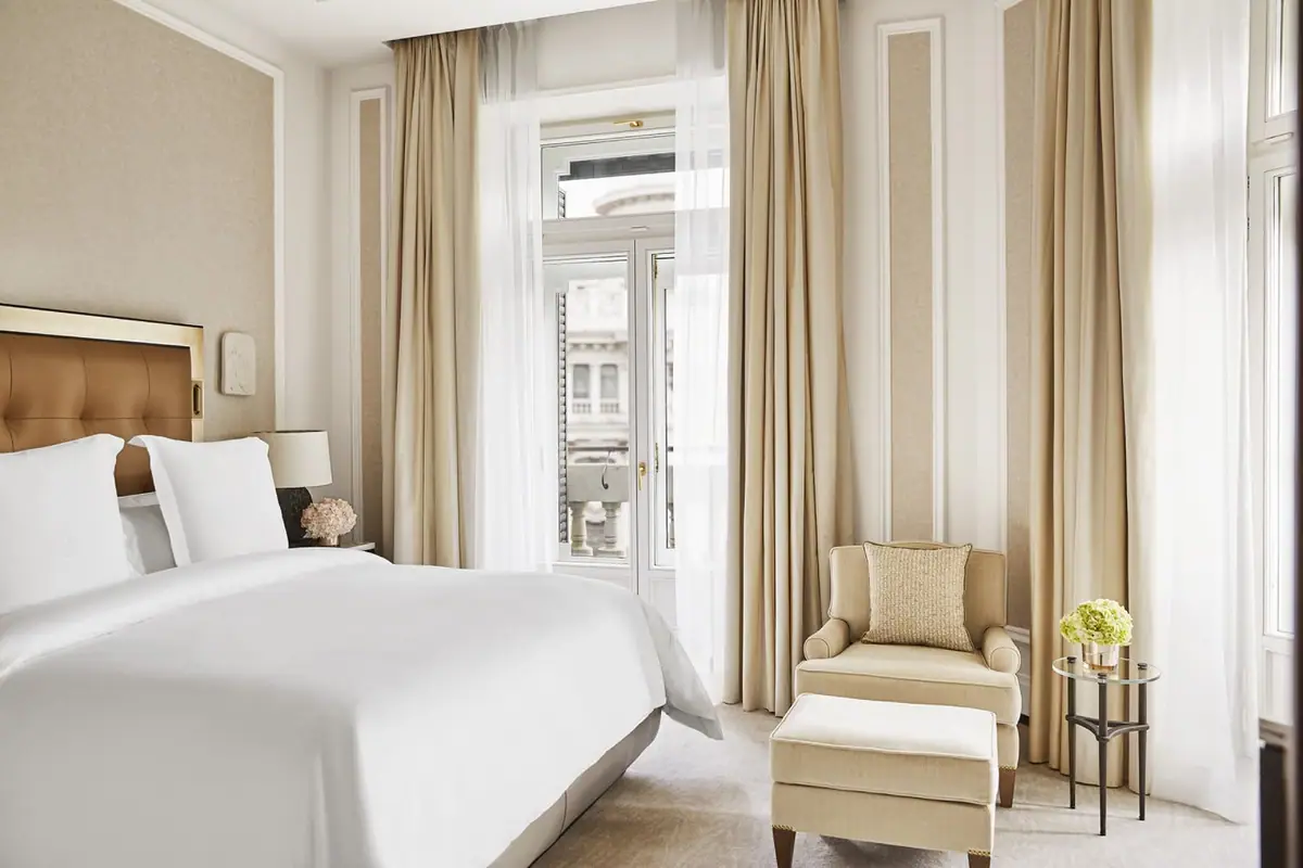 A guest room at Four Seasons Hotel Madrid with a tufted headboard and tall city windows