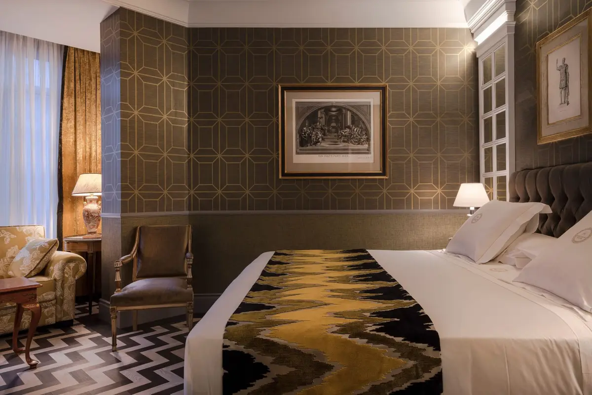 A junior suite bedroom at Heritage Madrid with a patterned runner and a dark wall