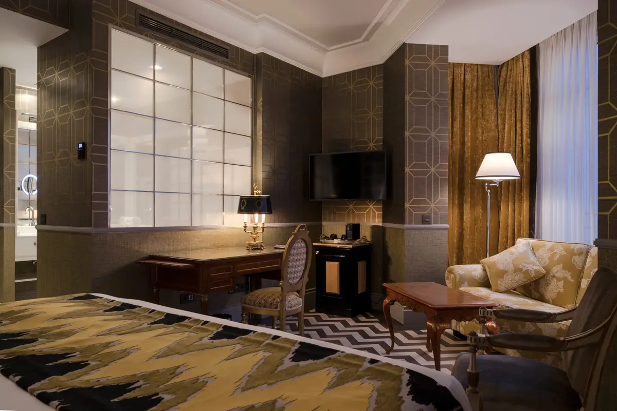 The sitting area of a junior suite at Heritage Madrid with a writing desk and tall windows