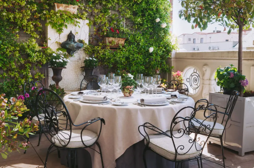 A laid table on the ivy covered terrace at Heritage Madrid with wrought iron chairs