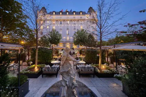 The Belle Epoque facade of the Mandarin Oriental Ritz Madrid lit at dusk above its garden