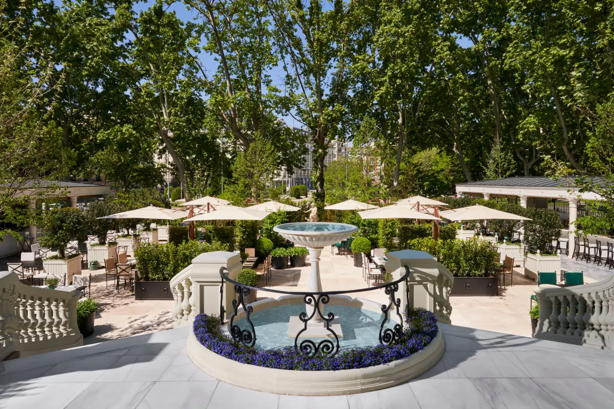 The garden terrace at Mandarin Oriental Ritz Madrid with a stone fountain and white parasols