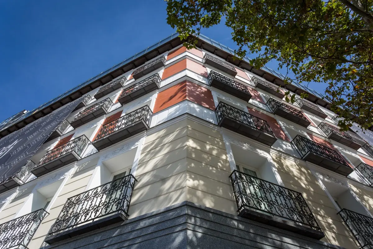 A close view up the balconied corner of Only YOU Hotel Atocha against a blue sky